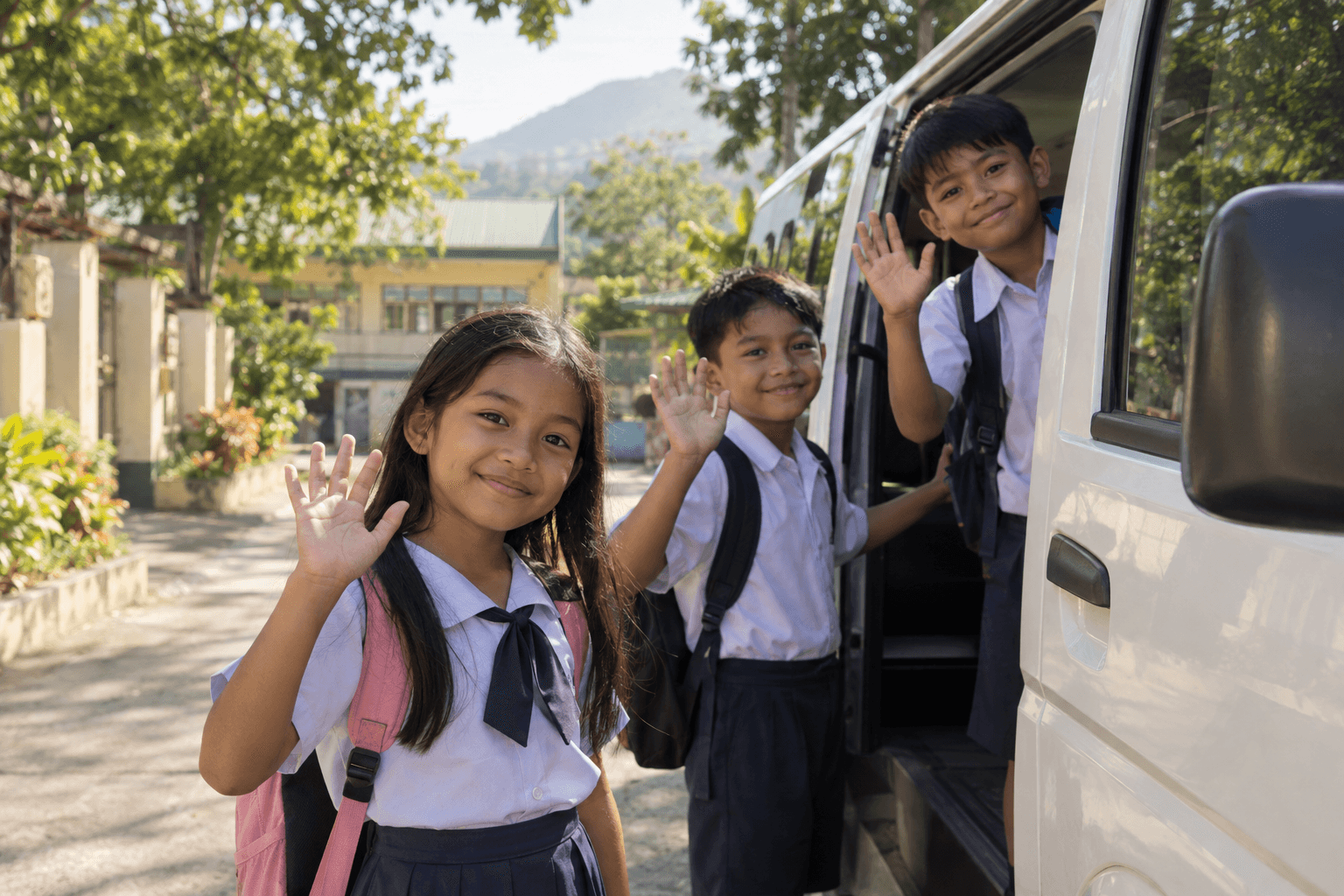 Generated illustrative scene of three schoolchildren waving beside a neighborhood school-transport van; fictional demo, not verified evidence